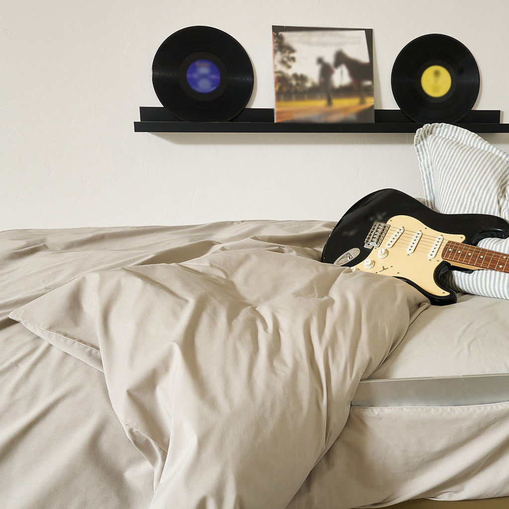 Twin XL Beige Duvet in a dorm room with a guitar on it over a Fitted Sheet with Full-Length Side Storage with a laptop inside and record albums decorating the wall.